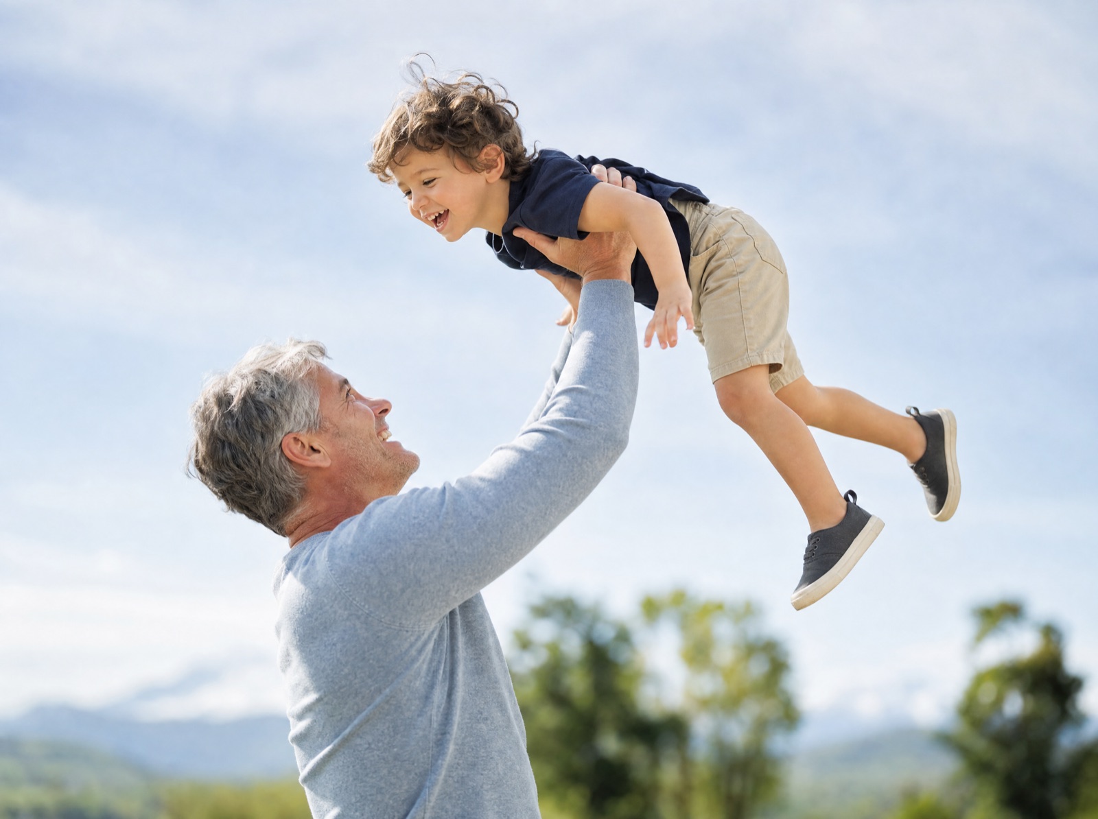 Grandfather lifting his grandchild outdoors